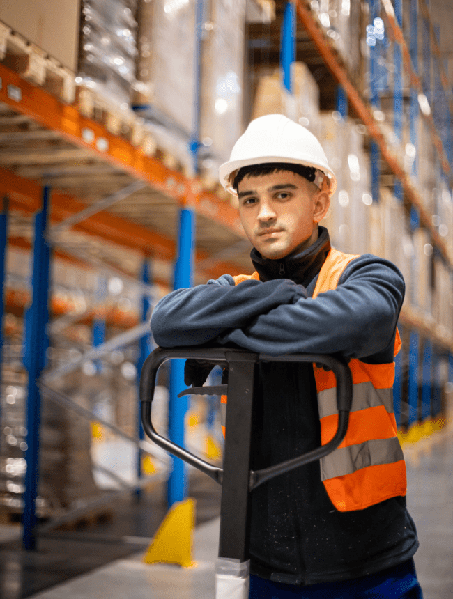 Pracownicy w odzieży odblaskowej przed budynkiem przemysłowym.